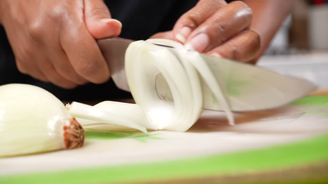 Slicing an organic onion to dice for a homemade recipe - side view isolated