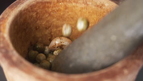 filling a mortar and pestle with chilies, garlic and green peppercorns