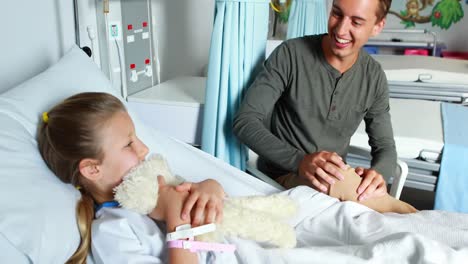 father giving teddy bear to her sick daughter