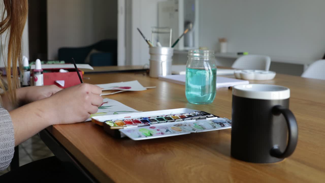 detalle de una mujer joven pintando con acuarelas