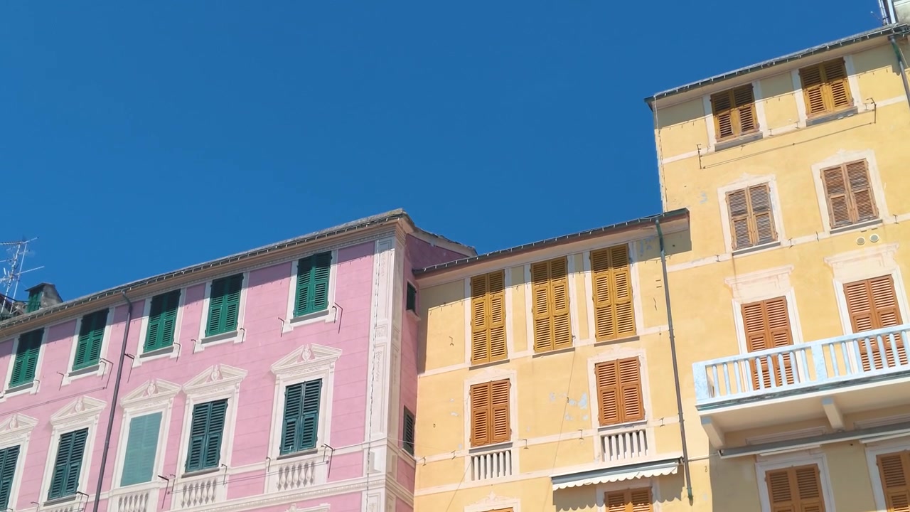 Plano inclinado en ángulo bajo de vibrantes apartamentos mediterráneos bajo un cielo azul claro de verano.
