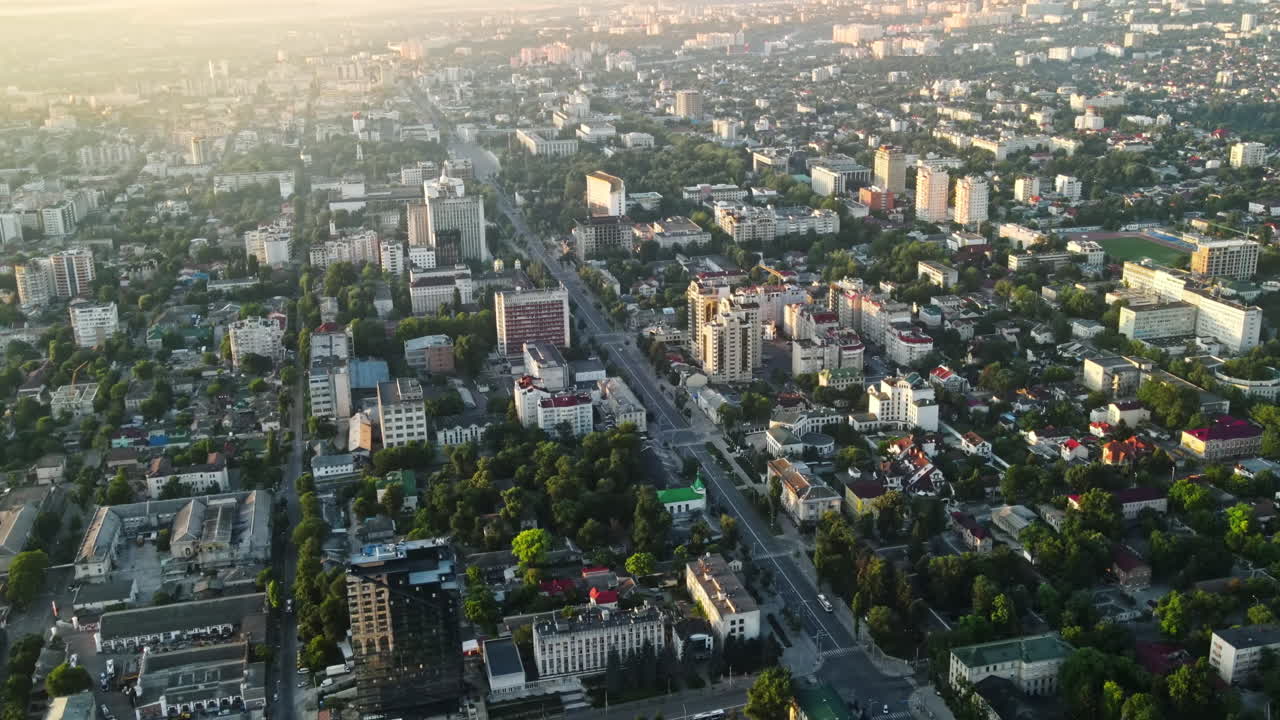 Aerial drone view of Chisinau at sunrise. Multiple buildings, trees, park, roads with cars. Moldova