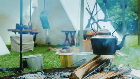 Native-American-Camp-In-The-Forest-Food-Is-Being-Prepared-In-The-Foreground-Traditional-Wigwam-Tents