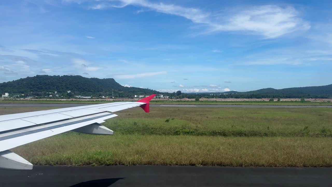 Plane view on runway with mountains in background, sunny blue sky