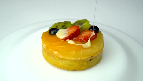 pouring cake with blueberry, kiwi, orange, strawberries on the plate rotation.