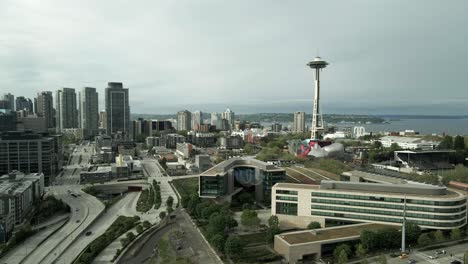 Día-Nublado-Sobre-El-Icónico-Horizonte-De-Seattle-Y-Frente-Al-Mar-En-La-Distancia,-Vía-Aérea