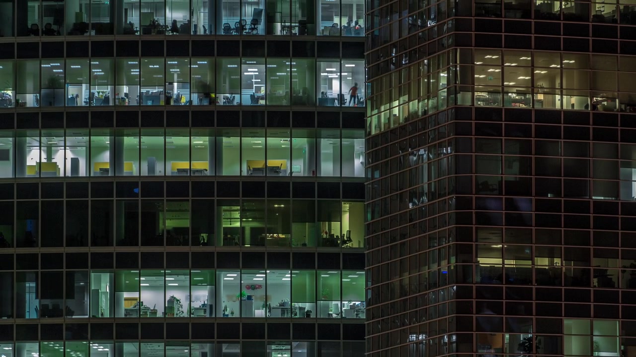 Vista de perto das janelas panorâmicas de escritórios nos arranha-céus do International Business Center da Cidade à noite, timelapse do alto.