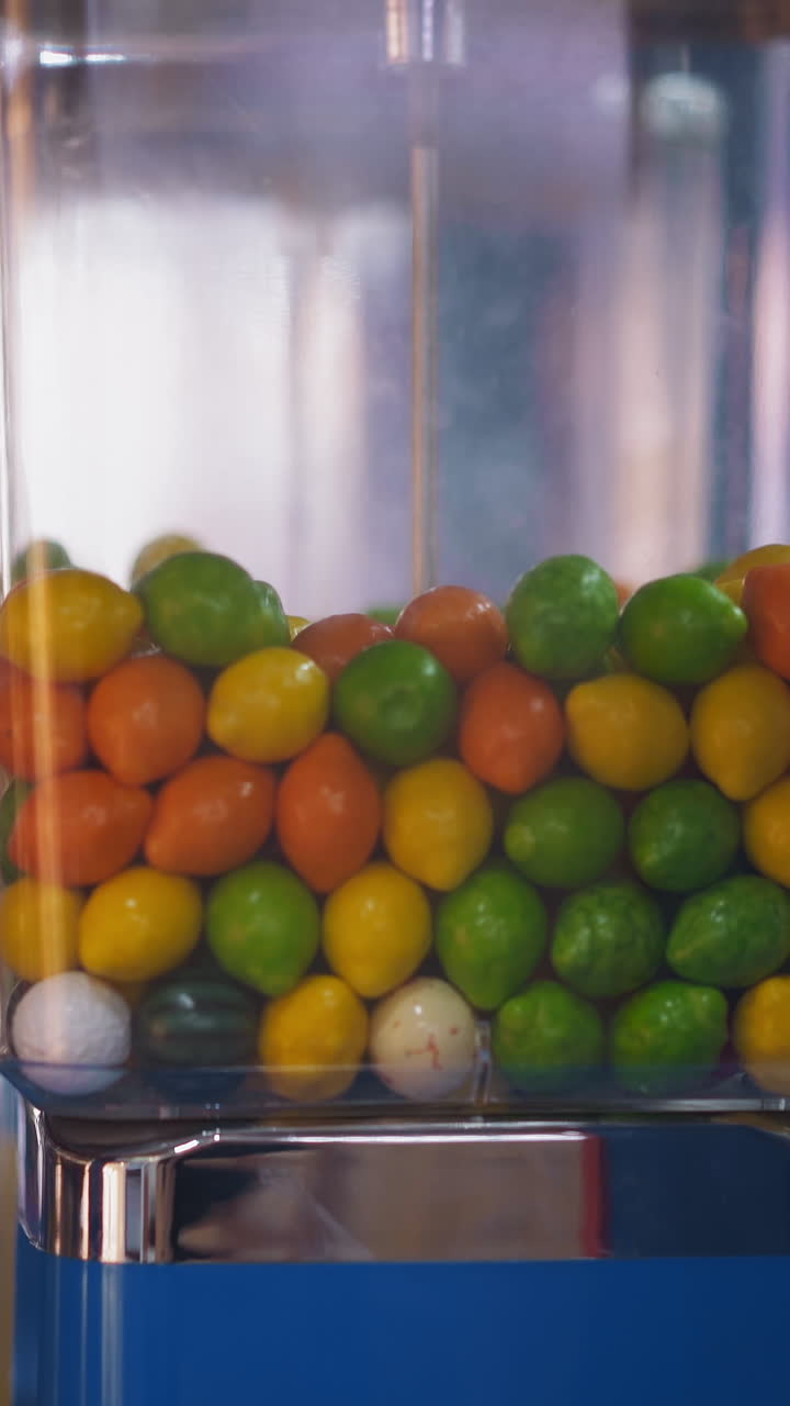 Gumball vending machine with plastic container full of candies installed on blurred background in hall of modern shopping mall closeup