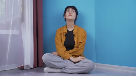 지친 사려 깊은 젊은 여성이 벽에 머리를 기대고.