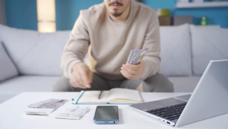 Hombre-Mirando-Facturas-Haciendo-Cálculos-Con-Calculadora-En-Casa.