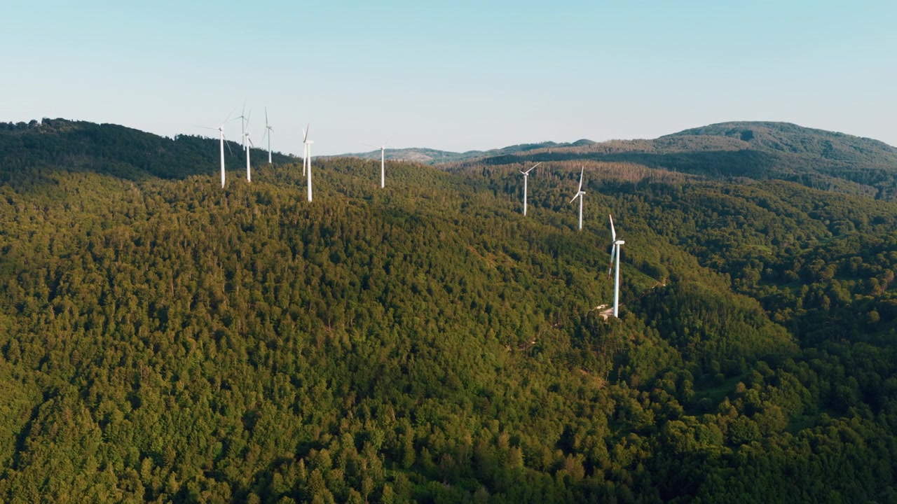 Wind Turbines on Lush Green Forested Hills at Sunset