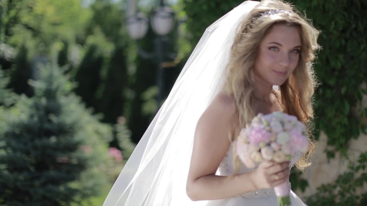 junge braut, die im park spazieren geht. porträt einer schönen lächelnden braut