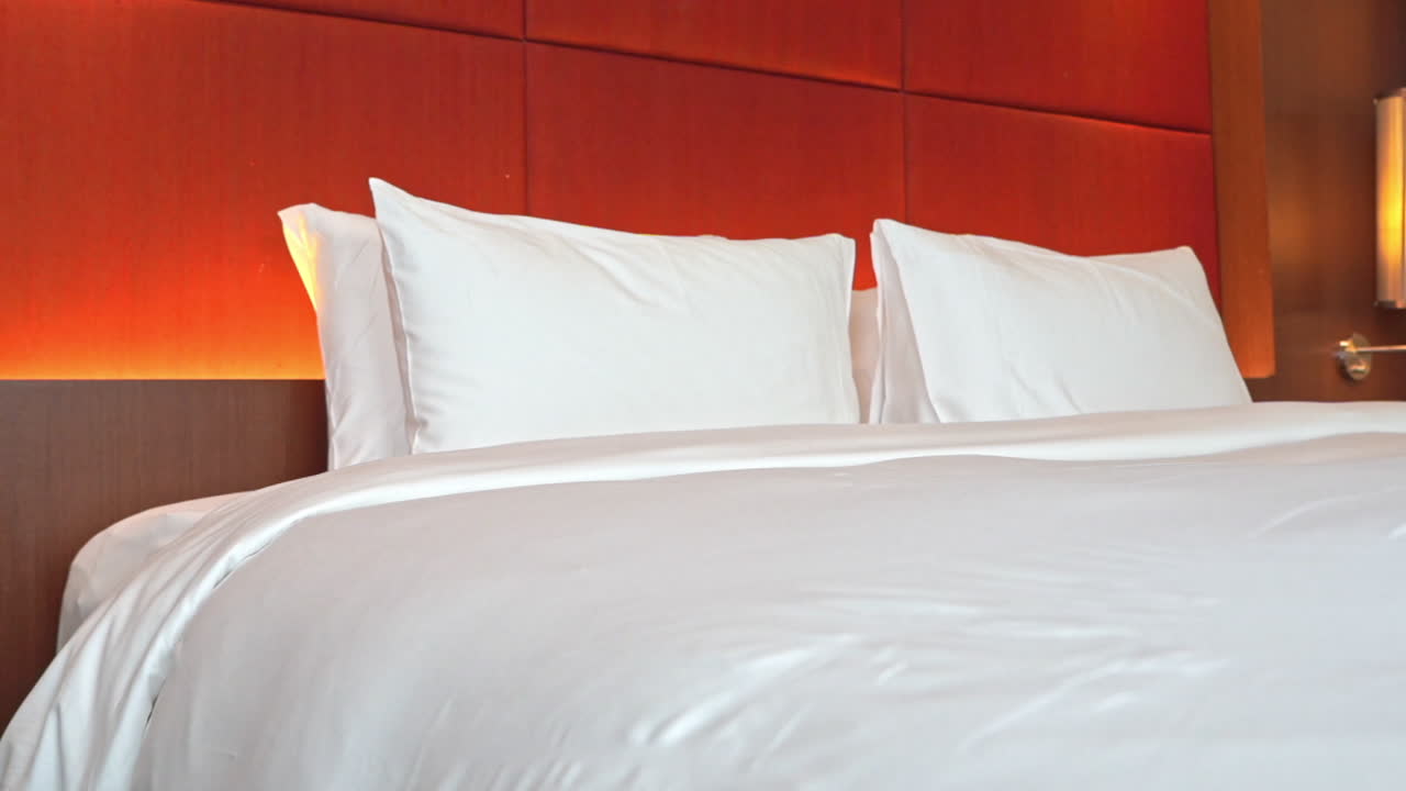 primer plano de una gran cama de hotel con un cabecero de color naranja