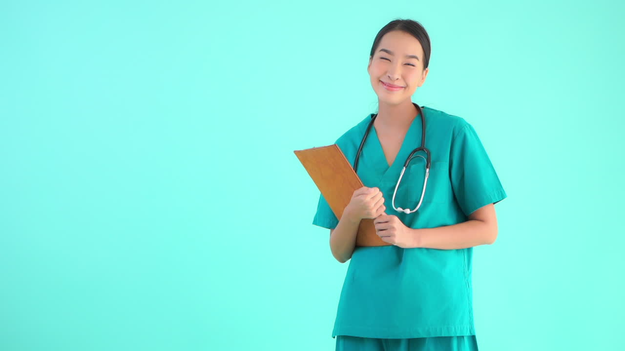 A young woman dressed in scrubs, stethoscope around her neck holds a chart in her hands. Copy space