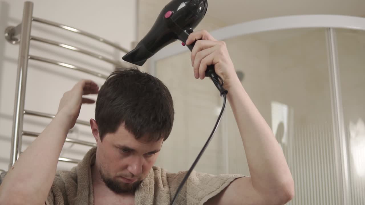 hombre secando el cabello en el baño