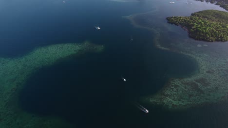 steady aerial shot of clear blue water and small island in the corner