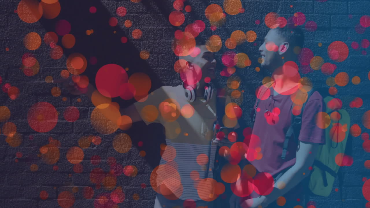 two friends using headphones and backpack, standing against brick wall, showing bokeh for marketing