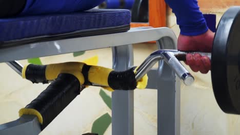 athletic sportive man laying down on bench lifting weight on machine in gym