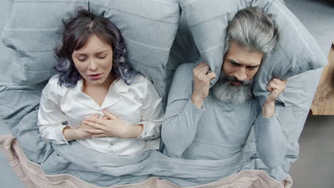 una pareja discutiendo en la cama.