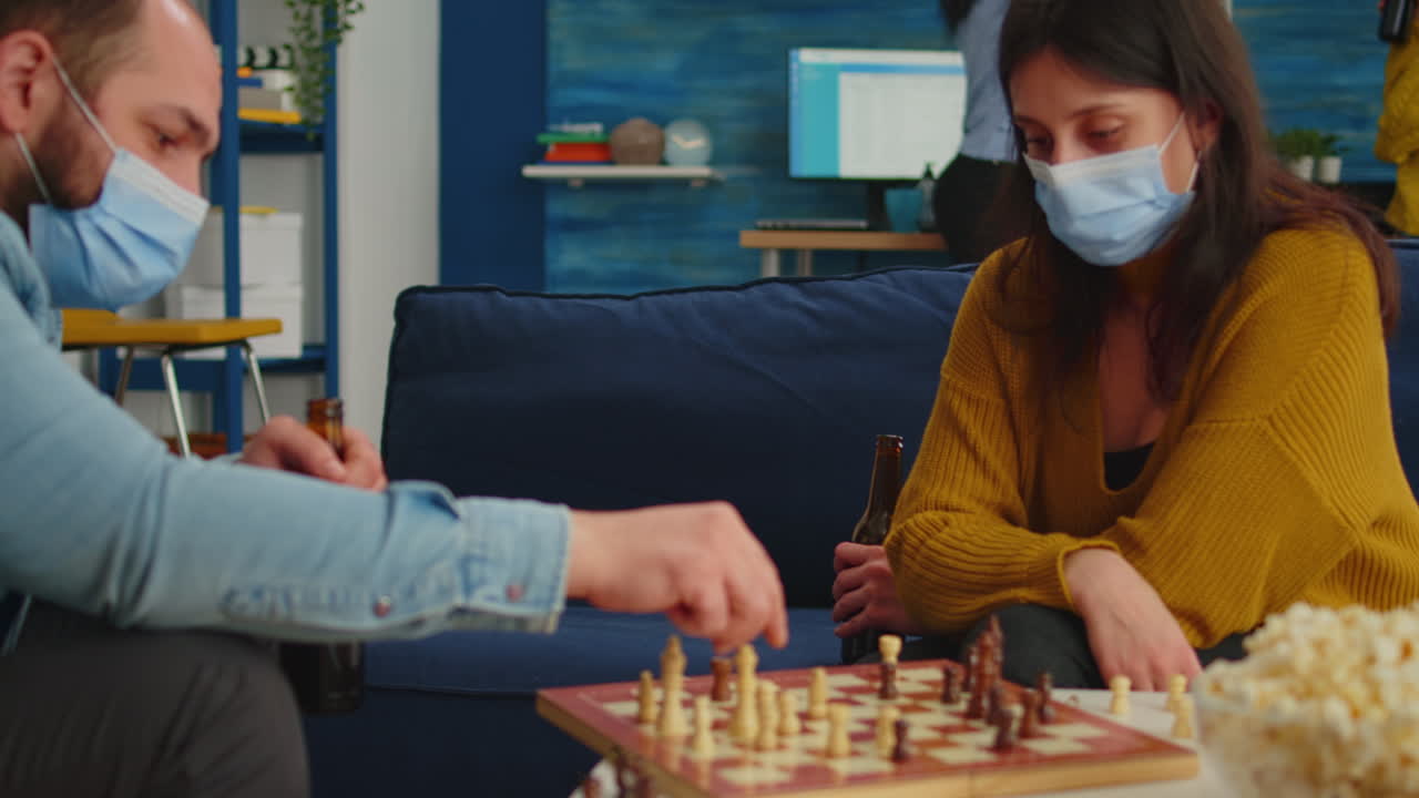 Friends with masks relaxing playing chess while drinking beer