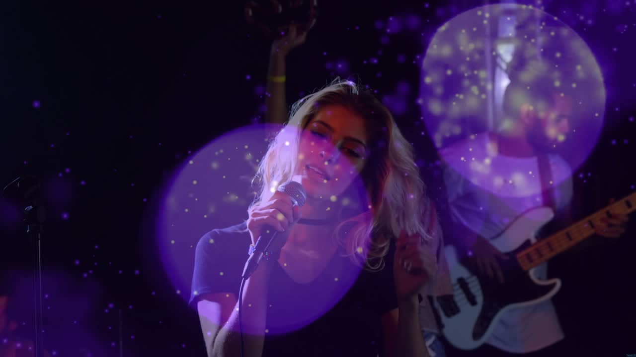 Lead vocalist lowering head to mic, causing hair flips while band singing, purple bokeh over stage