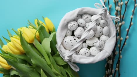 Holiday-contept-decoration-with-easter-eggs-and-yellow-tulips-over-blue