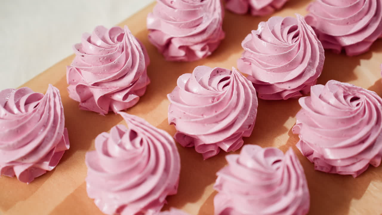 Close up of beautifully arranged swirl pink cupcakes on brown parchment paper with smooth creamy texture and natural lighting highlighting details, ready for baking