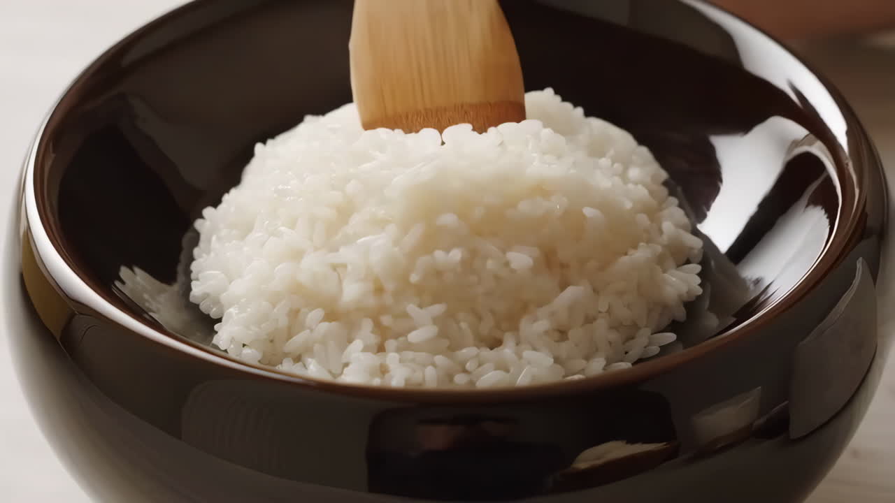 Serving White Rice in a Bowl with a Wooden Spoon
