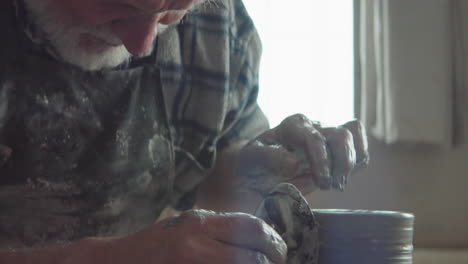 elderly potter throwing vase on wheel