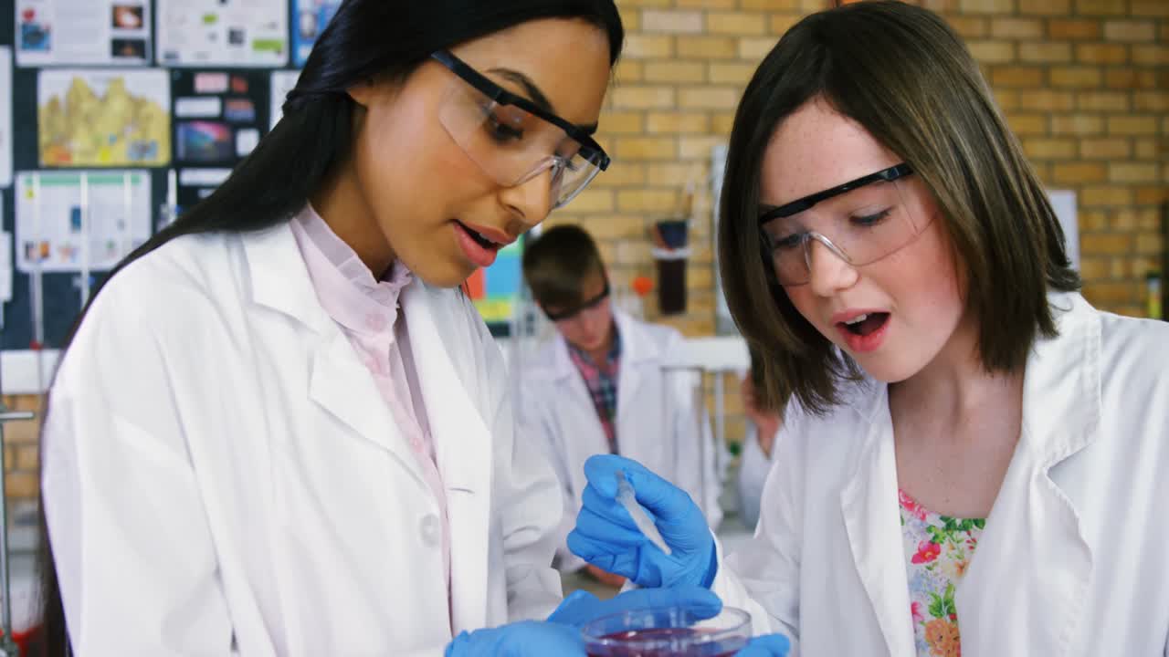 niñas experimentando con productos químicos en el laboratorio de la escuela