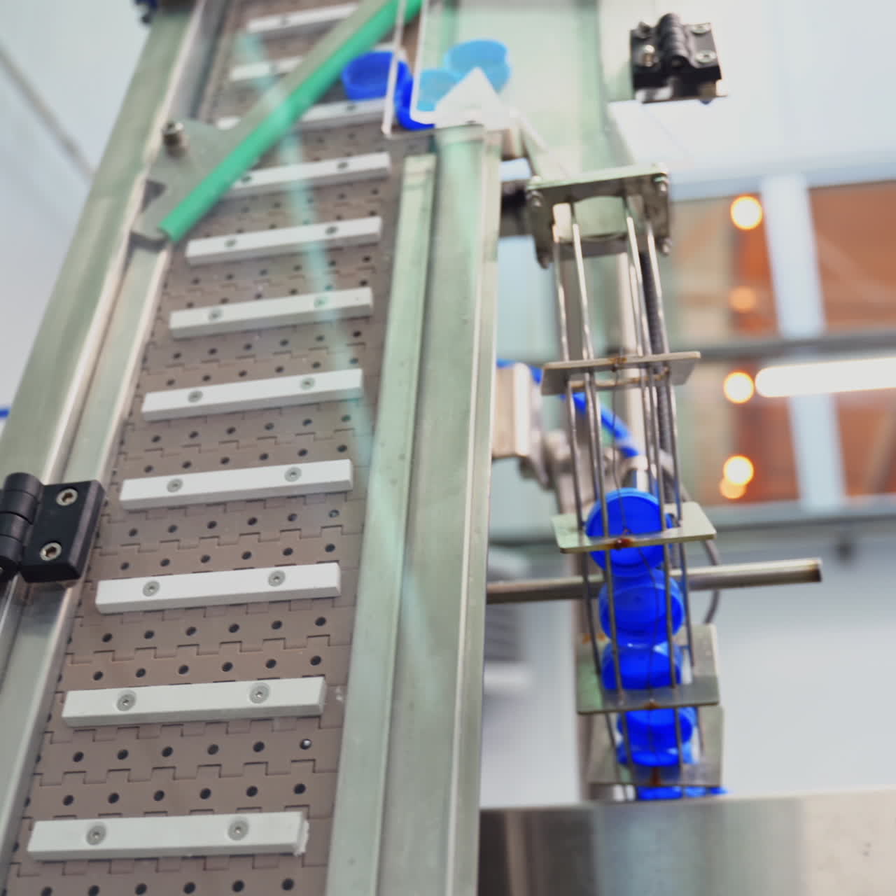 Automatic technology in a dairy factory. Modernized equipment in a plant. Conveyor line rising up with plastic lids for further packaging. Slow motion.