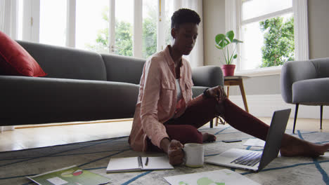 femme afro-américaine buvant du café tout en travaillant à la maison