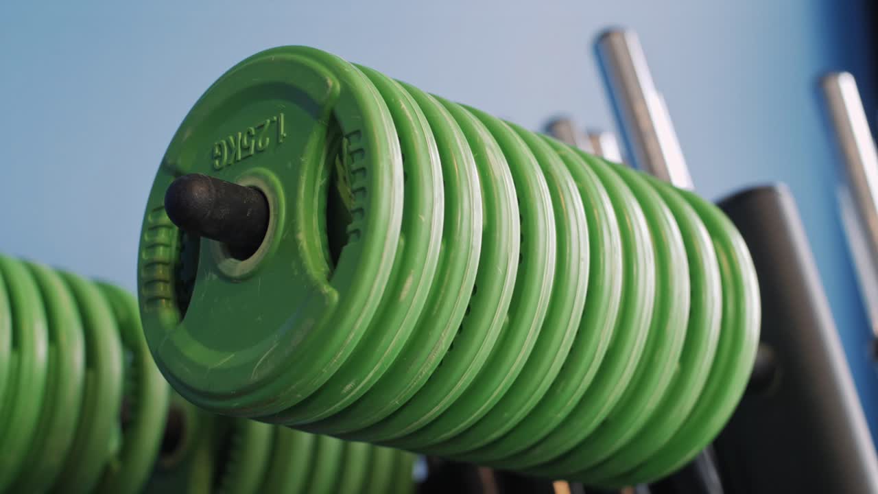 A detailed slow-motion capture of vibrant green weight plates lined up on a rack