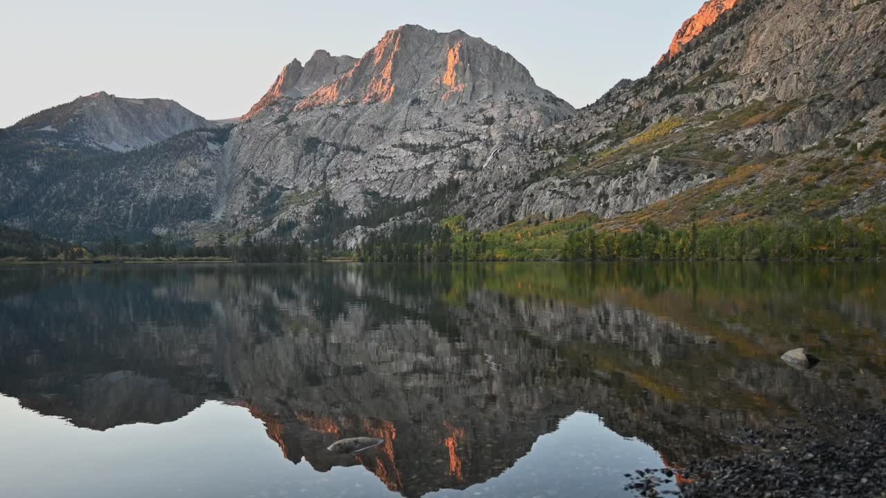 An early autumn sunrise, with the sunlight hitting the mountain and slowly moving down as the sun rises. Silver Lake in the Mammoth Lakes, Eastern Sierras, California