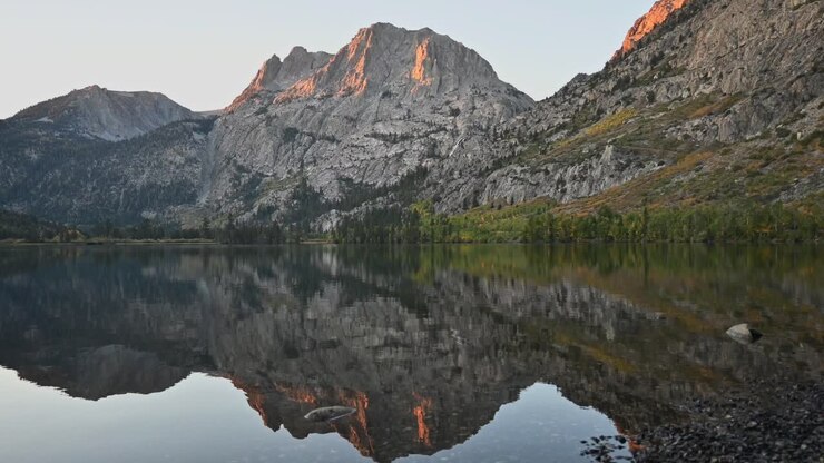 An early autumn sunrise, with the sunlight hitting the mountain and slowly moving down as the sun rises. Silver Lake in the Mammoth Lakes, Eastern Sierras, California
