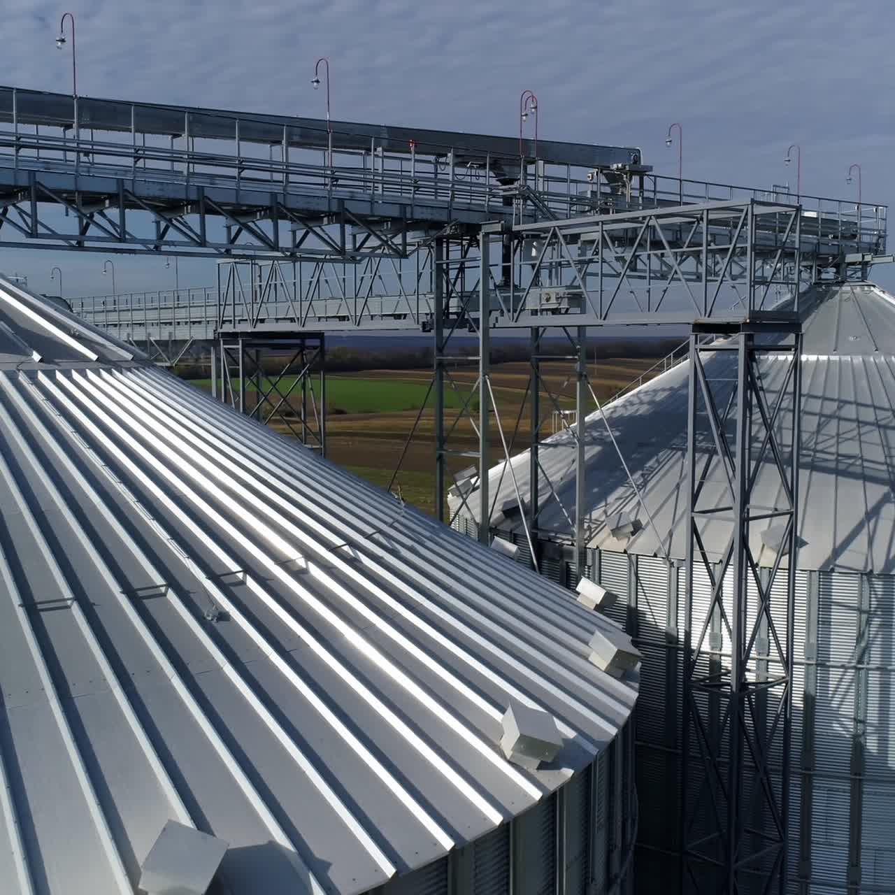 Tops of grain elevators. Modern silver granaries for grain storing and processing. Exterior of aluminum containers at sunlight. View from the air