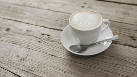 video of white cup of coffee with milk over wooden background