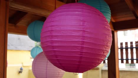 blue and pink paper lanterns hanging under a wooden structure