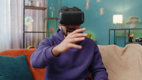 Man-using-virtual-reality-futuristic-technology-headset-to-play-simulation-3D-video-game-at-home