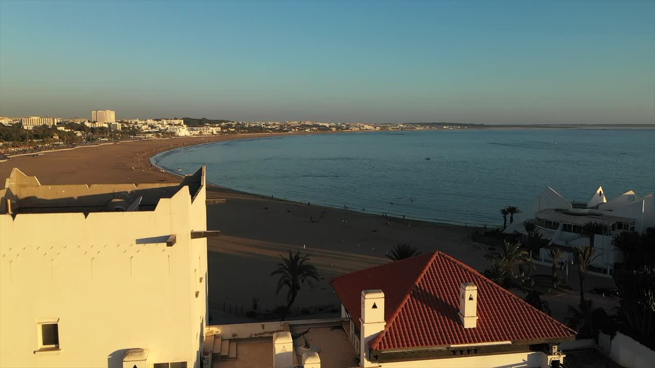 Vista aerea sui tetti degli hotel di Agadir verso la spiaggia e l'oceano all'ora d'oro, Marocco.