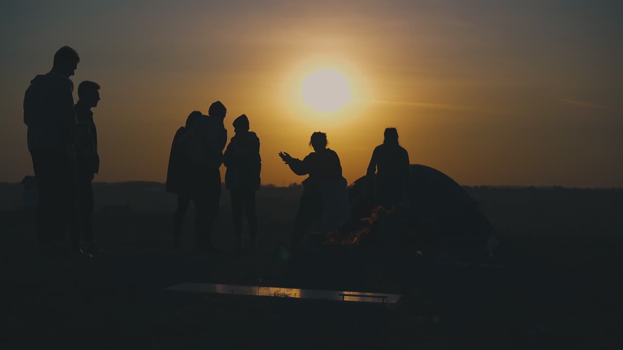 젊은 관광객 들 은 해 가 지는 시간 에 불타는 불 에서 휴식을 취 하고 있다
