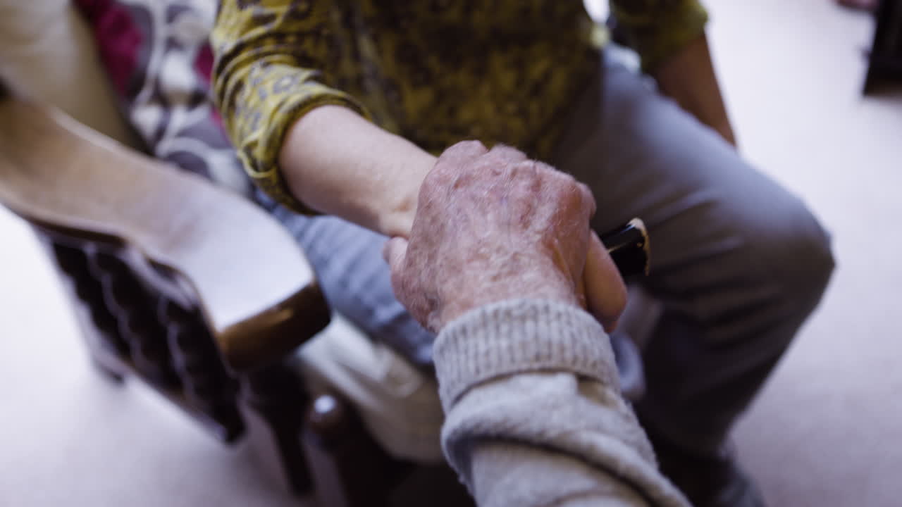 Close up of an elderly person's hand resting on a chair