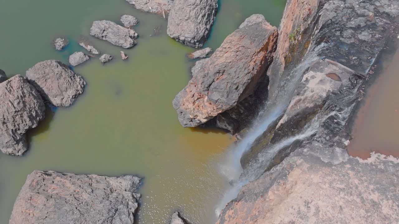 Aerial view of a waterfall cascading down rocky cliffs into a serene green lake