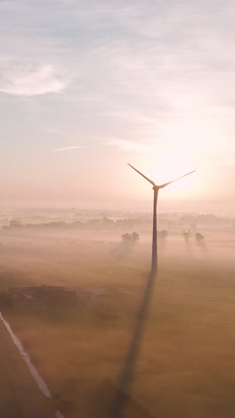 sunrise over a wind farm in a foggy landscape