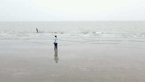 fotógrafo tomando una foto de un pescador tradicional tirando de su red en la playa de kuakata en bangladesh, asia, dron