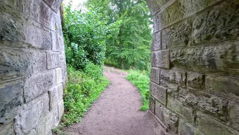 path through tunnel leading to lush greenery