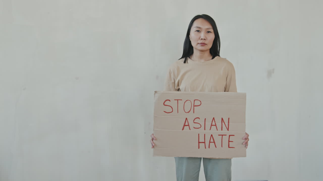 Asian Woman with Cardboard Stop Asian Hate Sign on White Background
