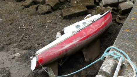 smashed damaged small old broken boat wreck stranded on fishing harbour rocks slow dolly right