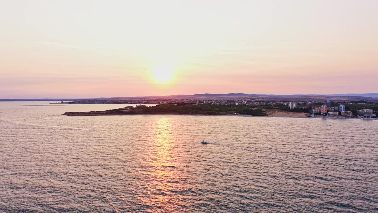 Vista del tramonto sul mare con una barca vicino alla riva in una zona costiera