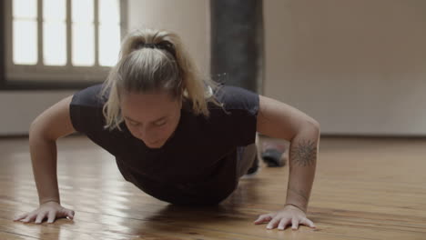 front view of focused caucasian woman doing push-ups in gym